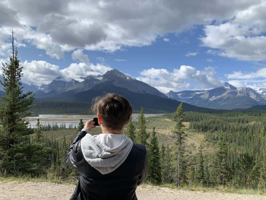 Woman taking a picture of the Banff scenery as a solo traveler