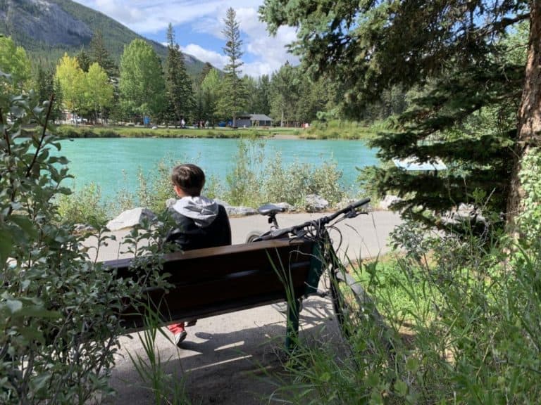 Woman resting on a bench next to the Bow River on the trail to Sundance Canyon in Banff.