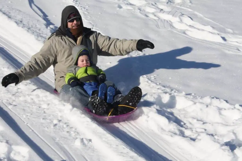 Father and son sliding down a hill in Banff on a toboggan.