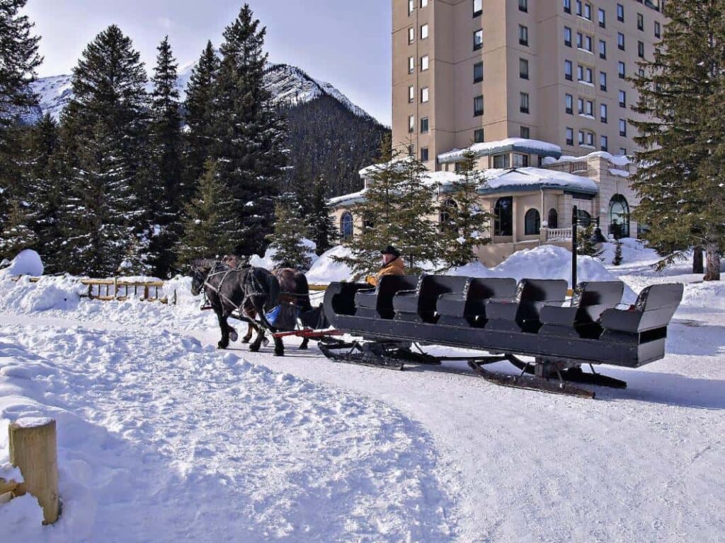 A horse-drawn sleigh and guide pass by the Fairmont Château Lake Louise. 