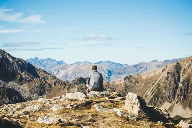 A solo hiker takes a rest on top of a mountain in Banff National Park.