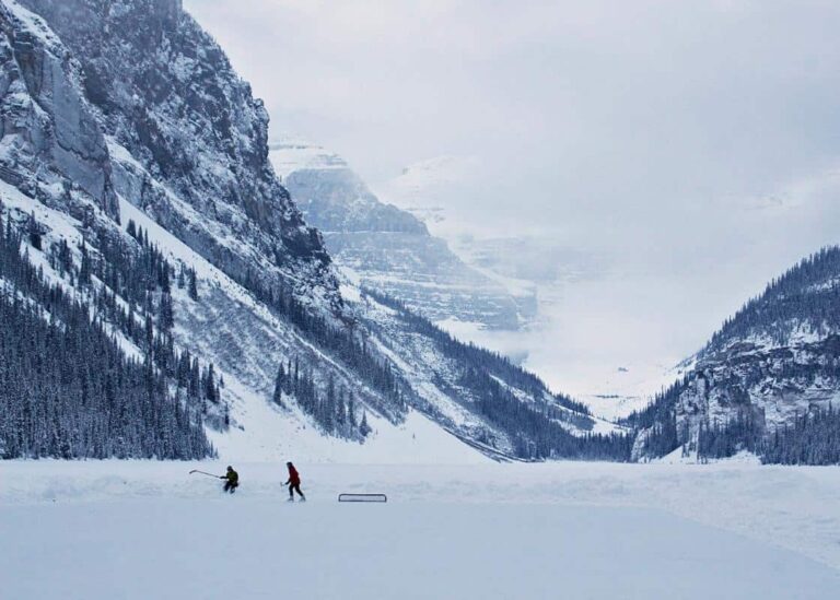 Two people playing hockey on a frozen Lake Louise in Banff