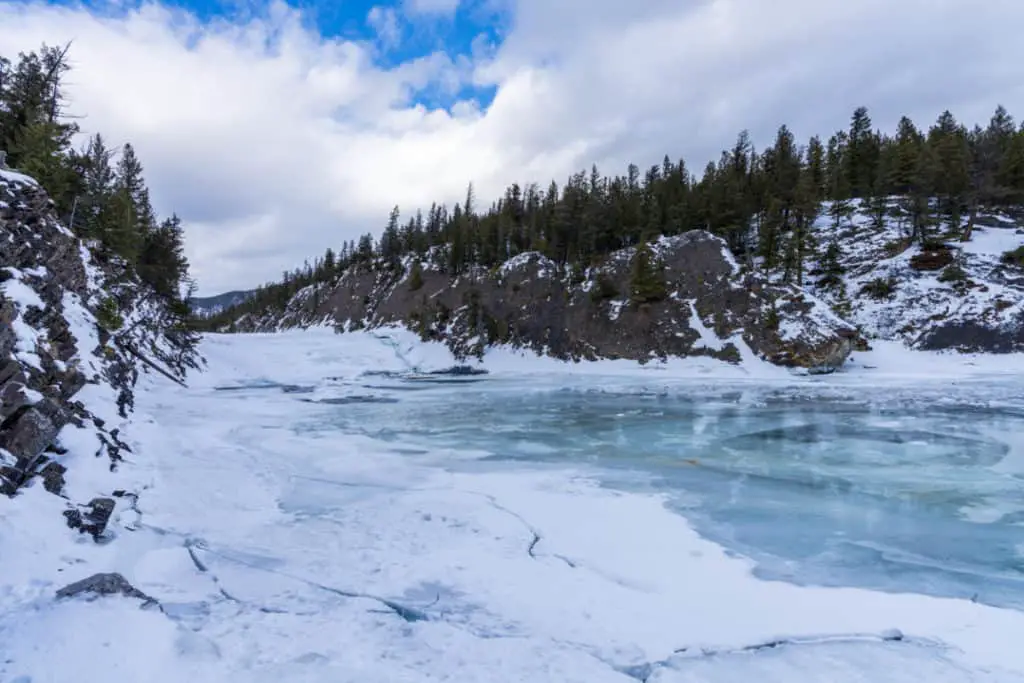 A frozen Bow Falls in a snow-capped landscape in Banff