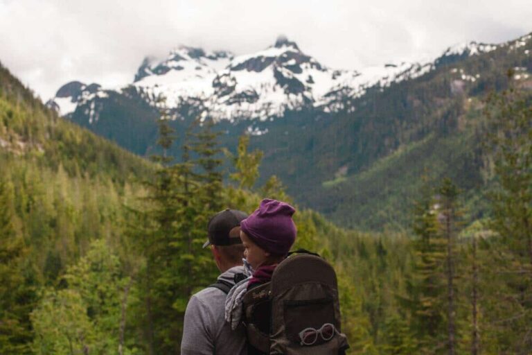 A father hiking in the Rocky Mountains with his baby on his back.