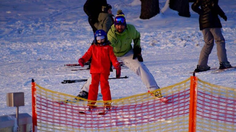 A kid is trying to learn to ski with his father in Banff