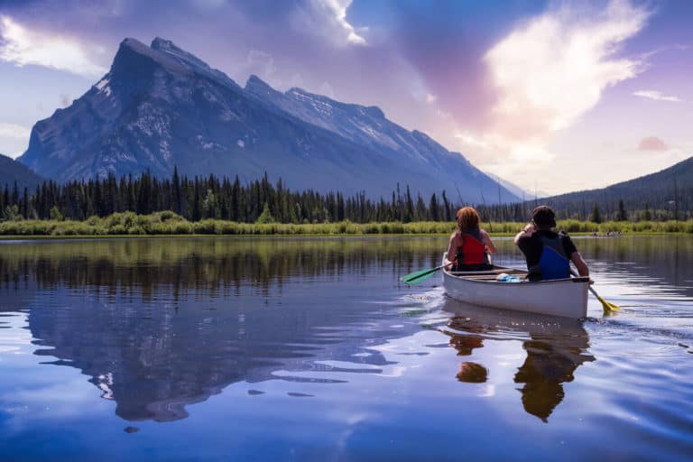 A couple are canoeing on Vermilion Lakes in Banff surrounded by mountains