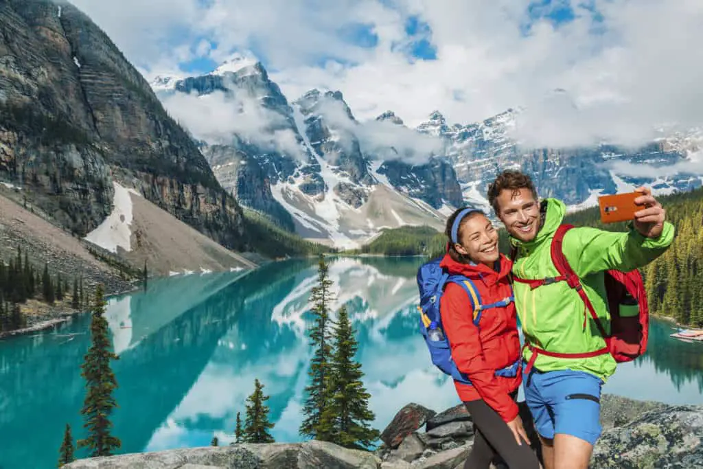 A couple taking a selfie  on a rock pile on the shore of Moraine Lake in Banff