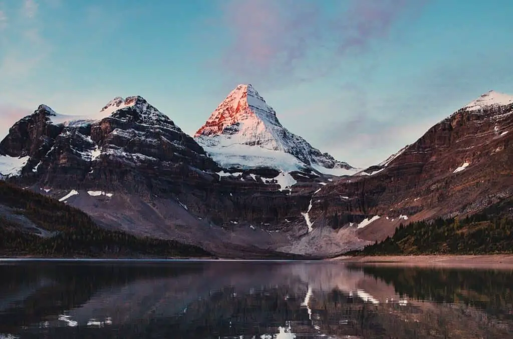 Mount Assiniboine under a clear sky reflecting off Magog Lake