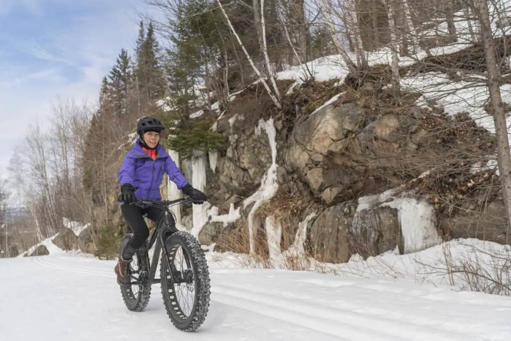 A woman on a fat bike in the snow on a mountain path in Banff National Park