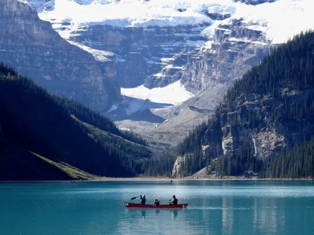A canoe with three people on Lake Louise with Mount Victoria rising above the lake in the background