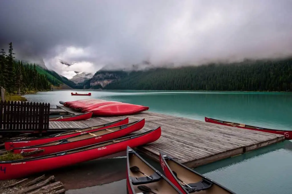 Red canoes lie on the dock at a misty Lake Louise in Banff National Park