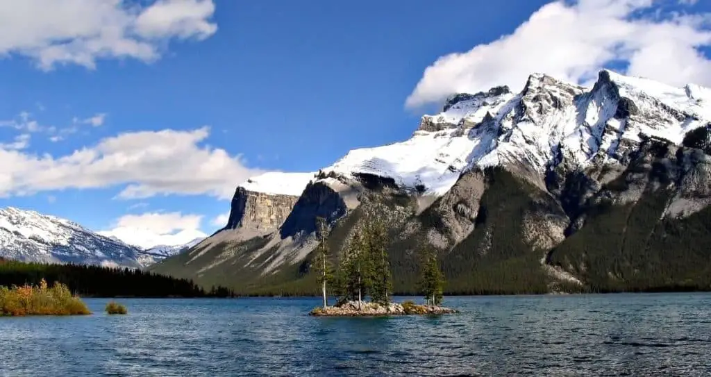 An island in Lake Minnewanka with the pointy peaks of the Rockies in the background