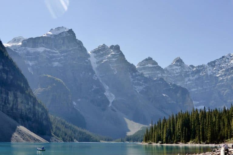 A man in a lonely canoe on a sunny Moraine Lake in Banff National Park