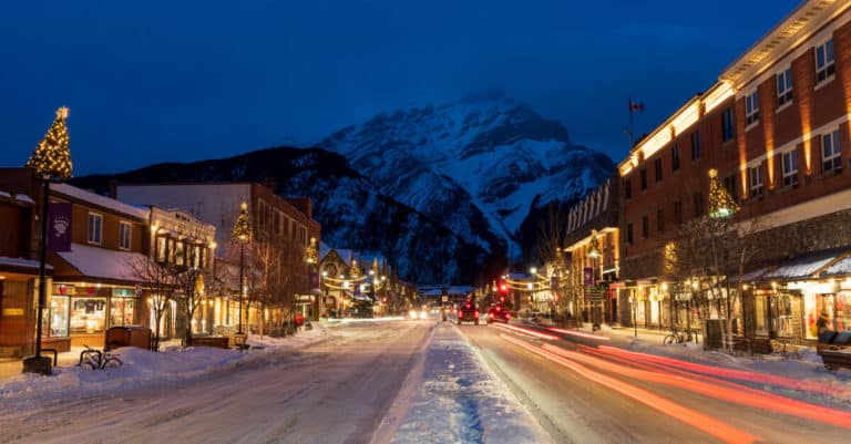 Banff Avenue at night, lit by several Christmas decorations and a Christmas tree standing on top of a restaurant