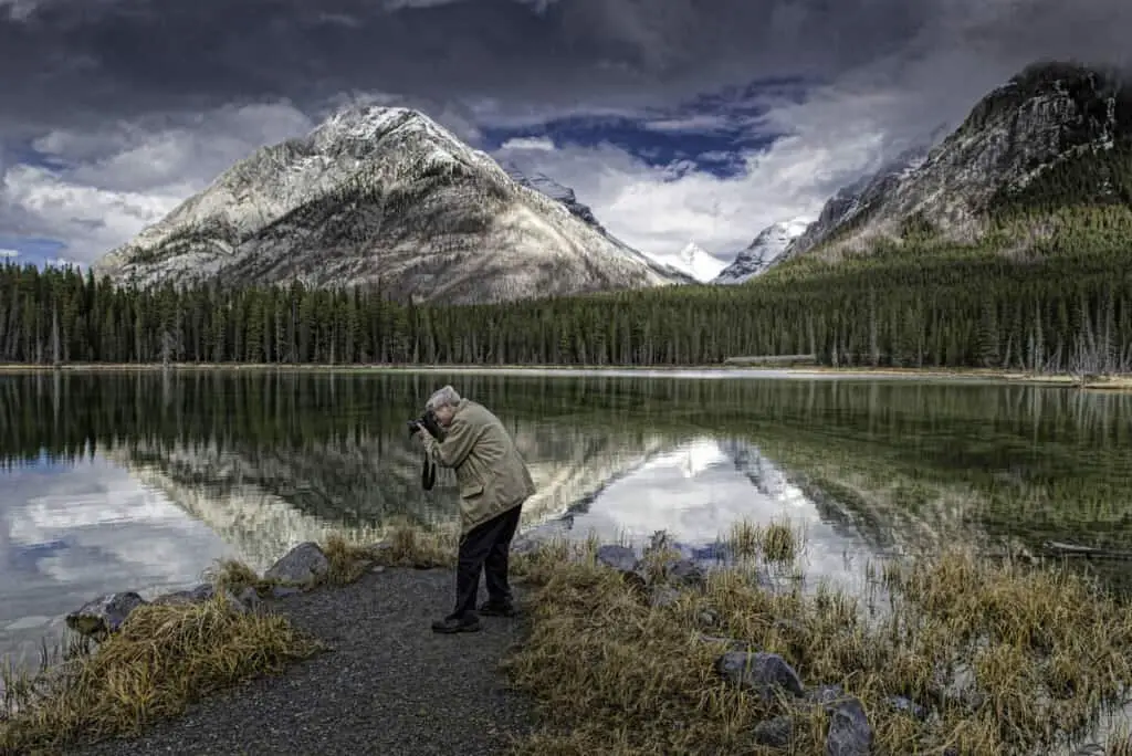 A man photographing a lake in Kananaskis Country