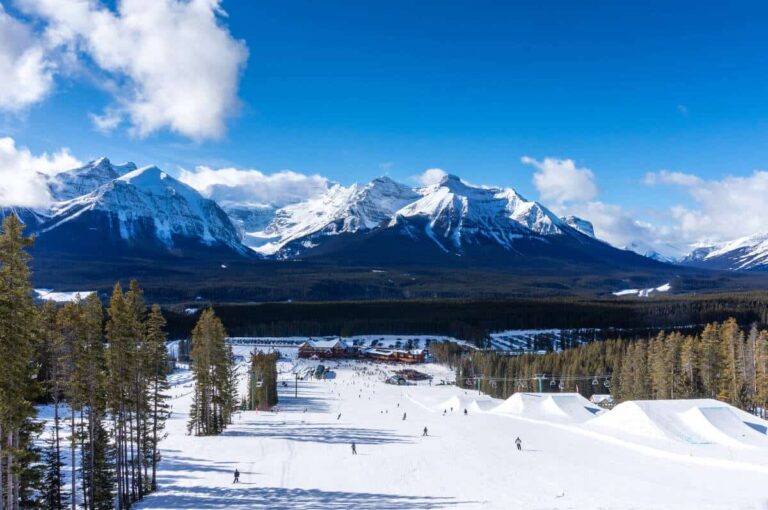 Skiiers and snowboarders descend the slopes at Lake Louise in the Canadian Rockies. Victoria Glacier can be seen in the background