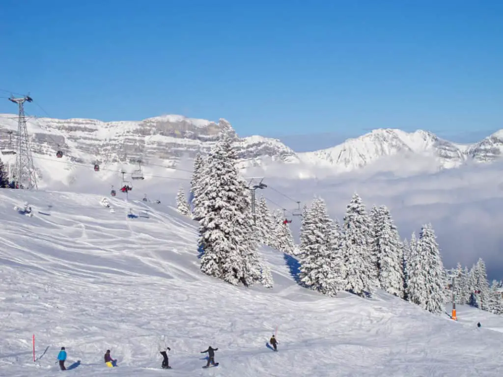 Skiers and snowboarders going downhill on fresh snow at Lake Louise ski resort in Banff National Park