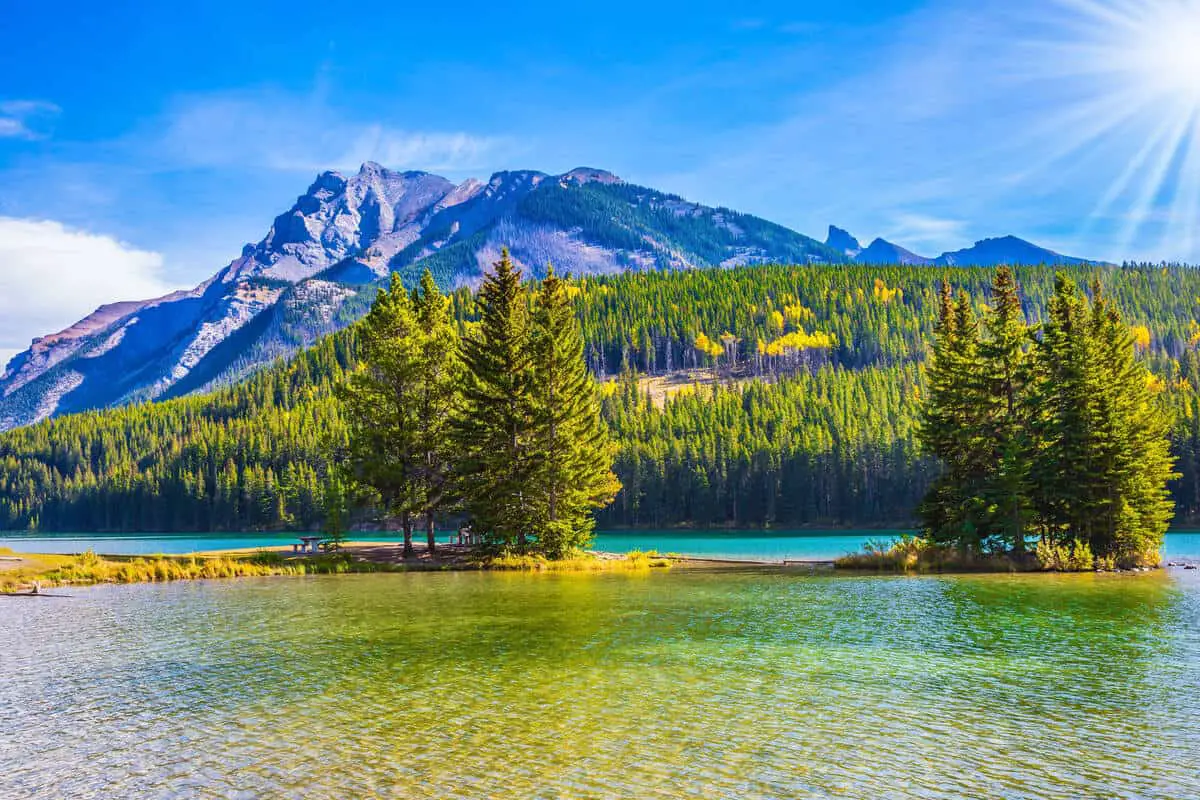 The sun shines over a lake in Banff National Park in a cloudless sky in July