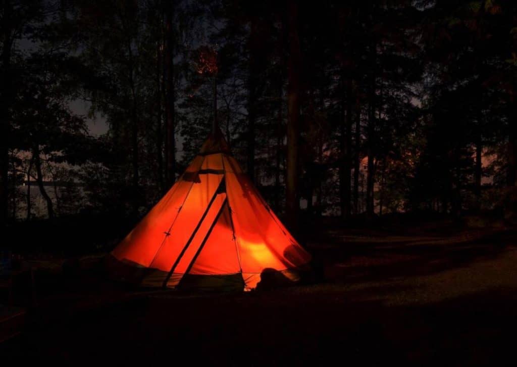 A lit tent among the trees at a campground in Banff National Park at night