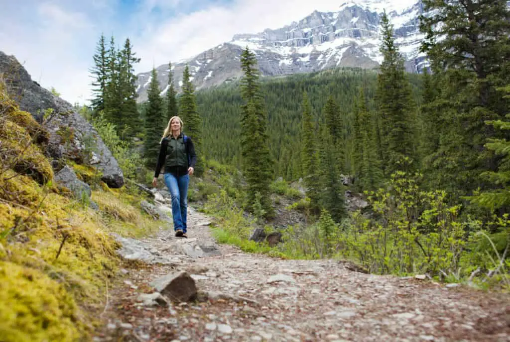 Blonde, happy woman hiking on a narrow path in the Rocky Mountains of Banff National Park