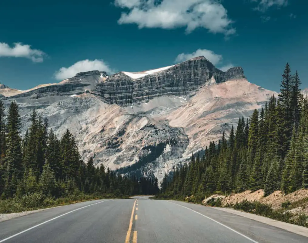 A deserted Icefields Parkway running to the horizon with a mountain dominating it