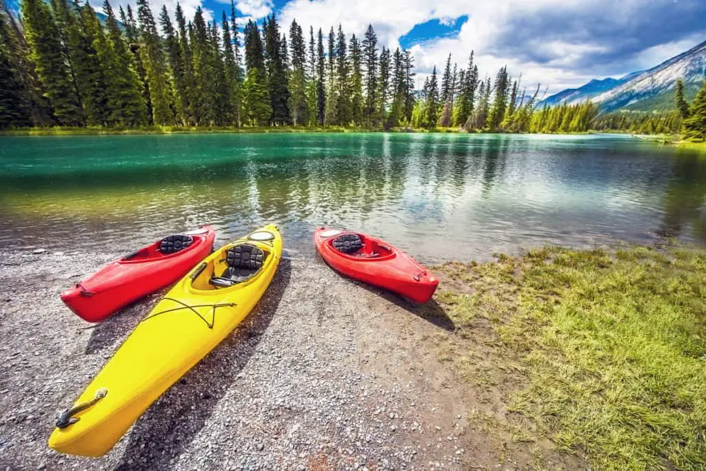 Kayaks lying at the shore of the Bow River near the Town of Banff on a cloudy summer day.