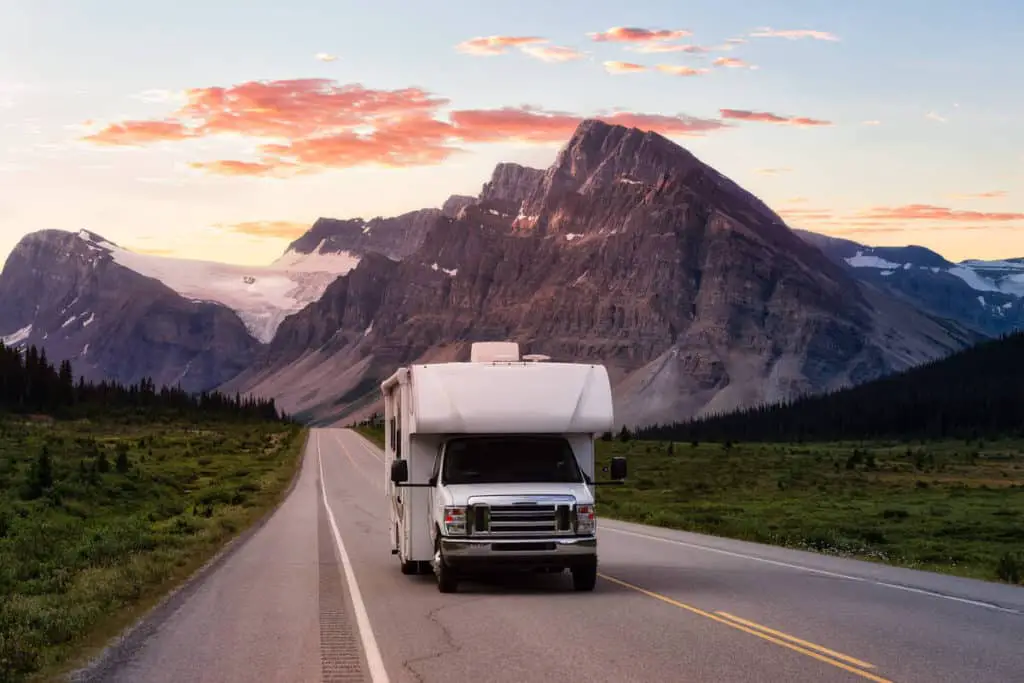 An RV drives on the Icefields Parkway in Banff on a vibrant sunny evening in summer