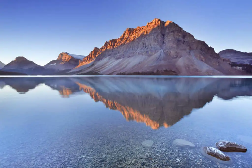 The mountains around Bow Lake reflecting in the water at sunrise