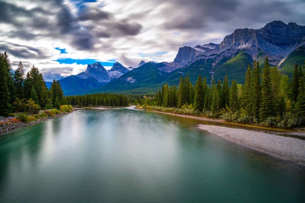 The turquoise waters of the Bow River with in the background the famous Three Sisters rising high above