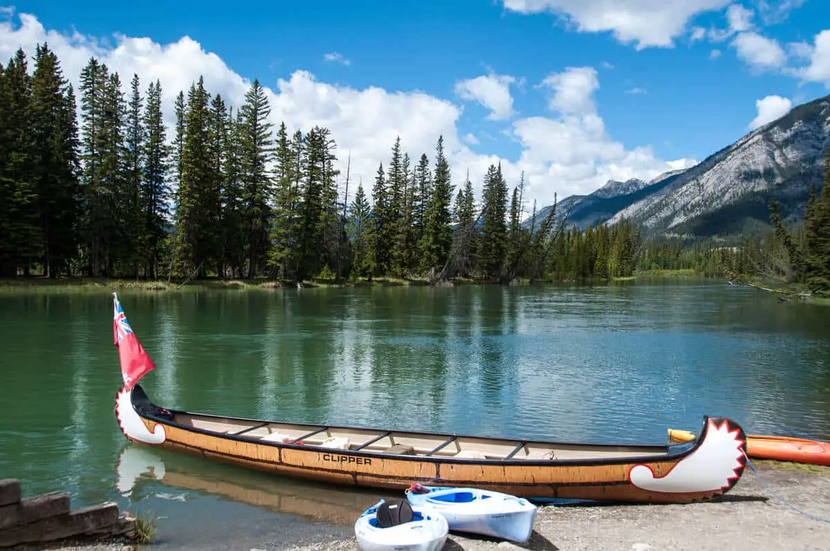 A big canoe named Clipper waiting on the shore of Bow River, waiting for passengers, near the town of Banff