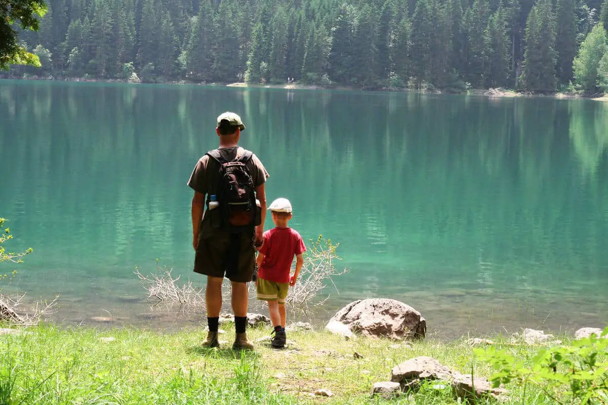 A father and son admiring the turquoise blue waters from an unkown glacial lake during a hike in Banff National Park