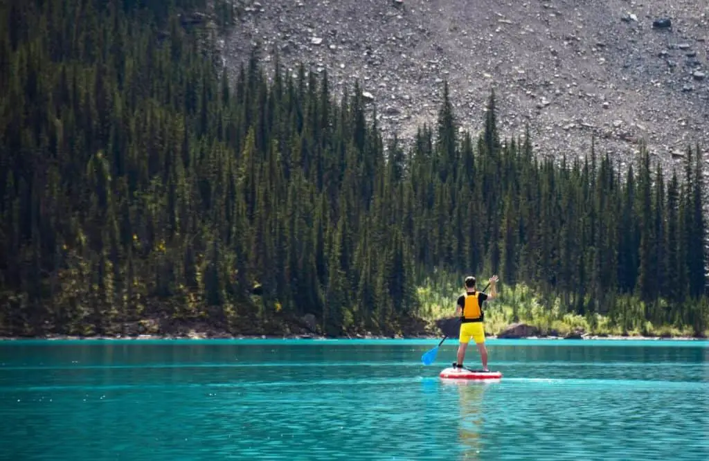 A man on a SUP on the turquoise water the Canadian Rockies are known for