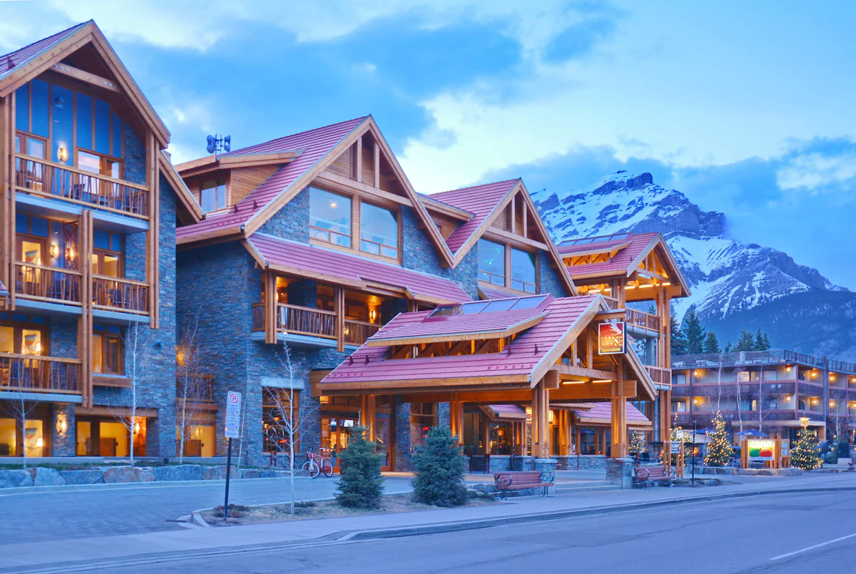 The exterior of Moose Hotel and Suites on Banff Avenue with a snowy Cascade Mountain in the background.