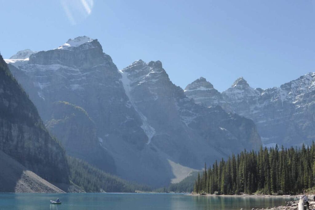 Moraine Lake on a hot summer day with a lone man in a canoe on the turquoise water