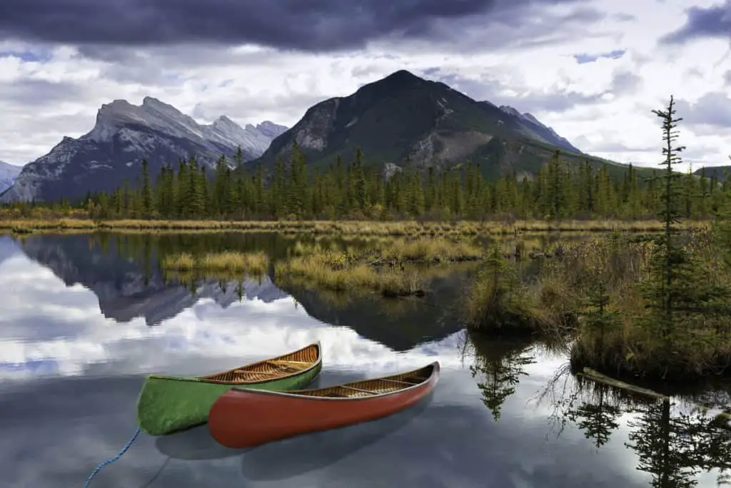 A green and a red canoe on Vermilion Lakes, waiting for people