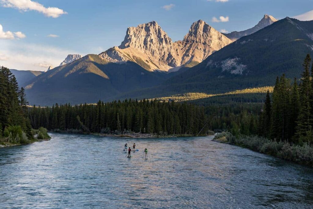 Four people float on the Bow River near Canmore with the impressive Three Sisters towering high above