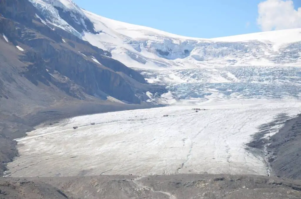 Several Ice Explorers seen in the distance riding on the enormous Athabasca Glacier near the Icefield Parkway