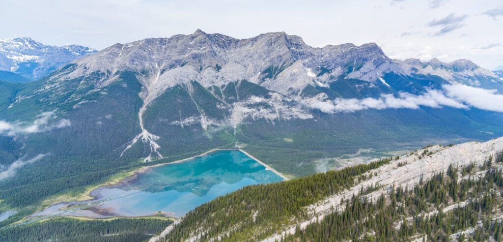 An aerial view of a lake and the surrounding Rocky Mountains in Banff National Park, seen from a helicopter