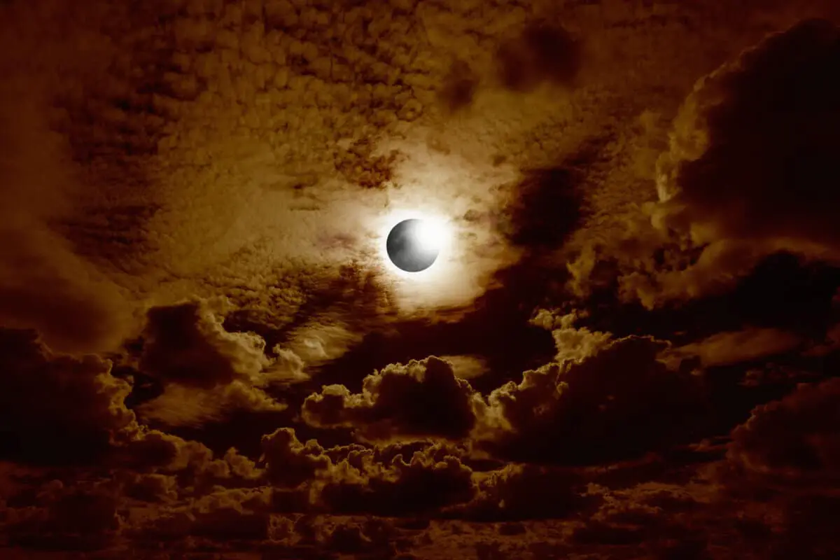 A full solar eclipse in a cloudy sky, creating a brown gloom