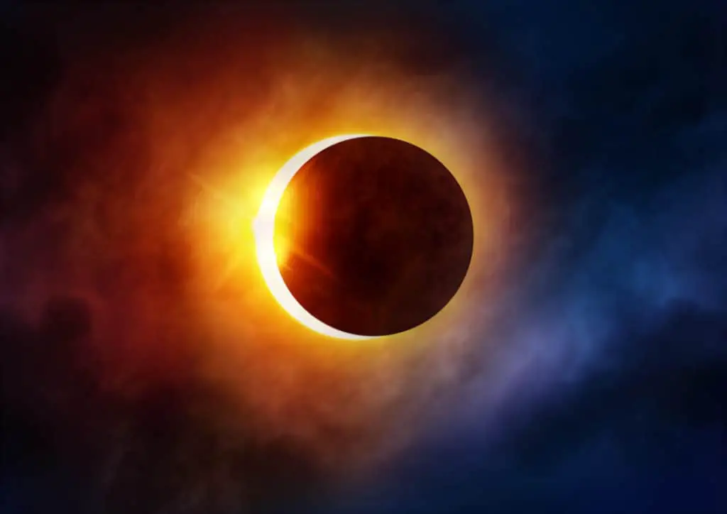 An almost full solar eclipse against colorful skies