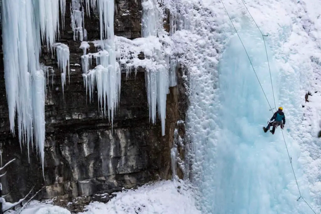 A man scaling a frozen waterfall in Johnston Canyon in Banff National Park