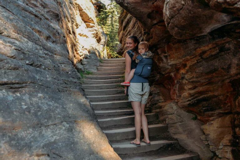 A mother carries her toddler on her back while hiking through a empty canyon near Athabasca Falls