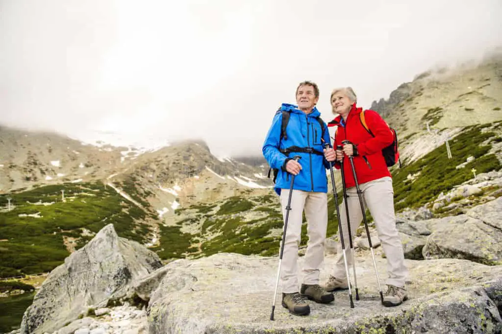 An elderly couple holding trekking poles while enjoying the barren landscape of Banff National Park above the tree line