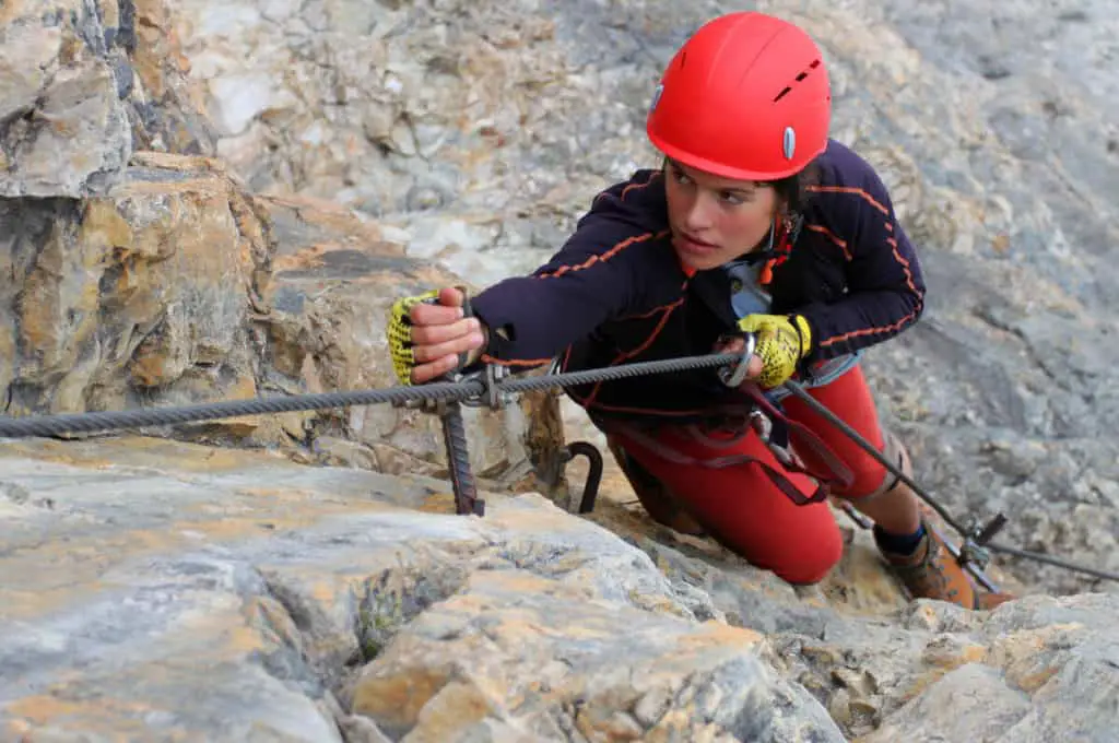 A woman is scaling a cliff on the Mount Norquay via ferrata course