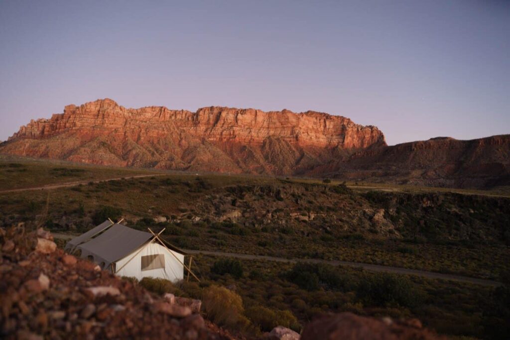 A glamping tent of Under Canvas out in a rocky field in Zion National Park during sunset over Utah, United States