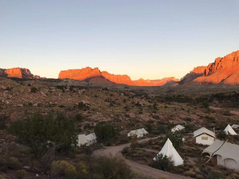 Gamping tents of Under Canvas near a rocky dirt road in Zion National Park during sunset over Utah, United States